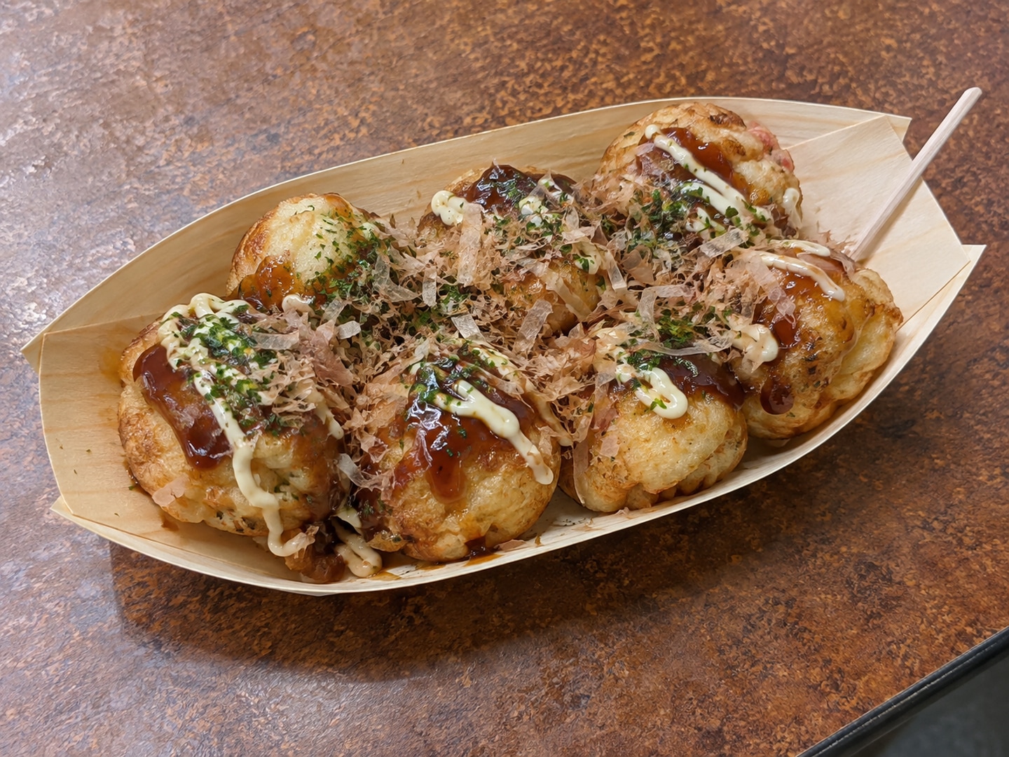 Illustration of takoyaki with sauce and bonito flakes in a wooden takeaway boat